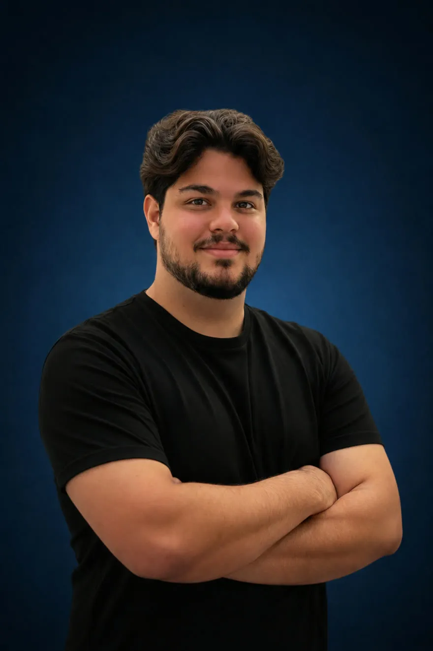 Mateus Alex, de braços cruzados, sobre fundo azul